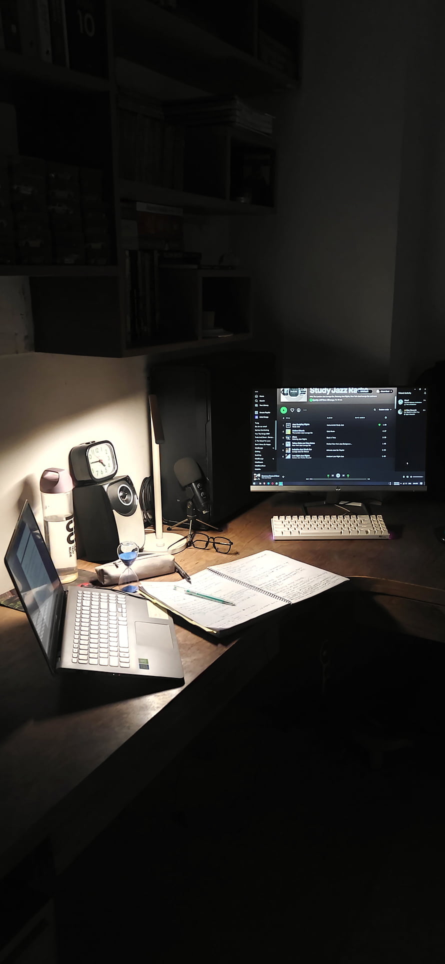 Dimly lit home office desk with laptop, monitor, and notebook for late night study HD phone wallpaper
