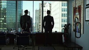 Two Men in Suits Standing in a High-Rise Office with City View HD wallpaper