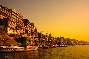 Varanasi Ghats Along the Ganga River at Golden Hour with Boats and Temples HD wallpaper