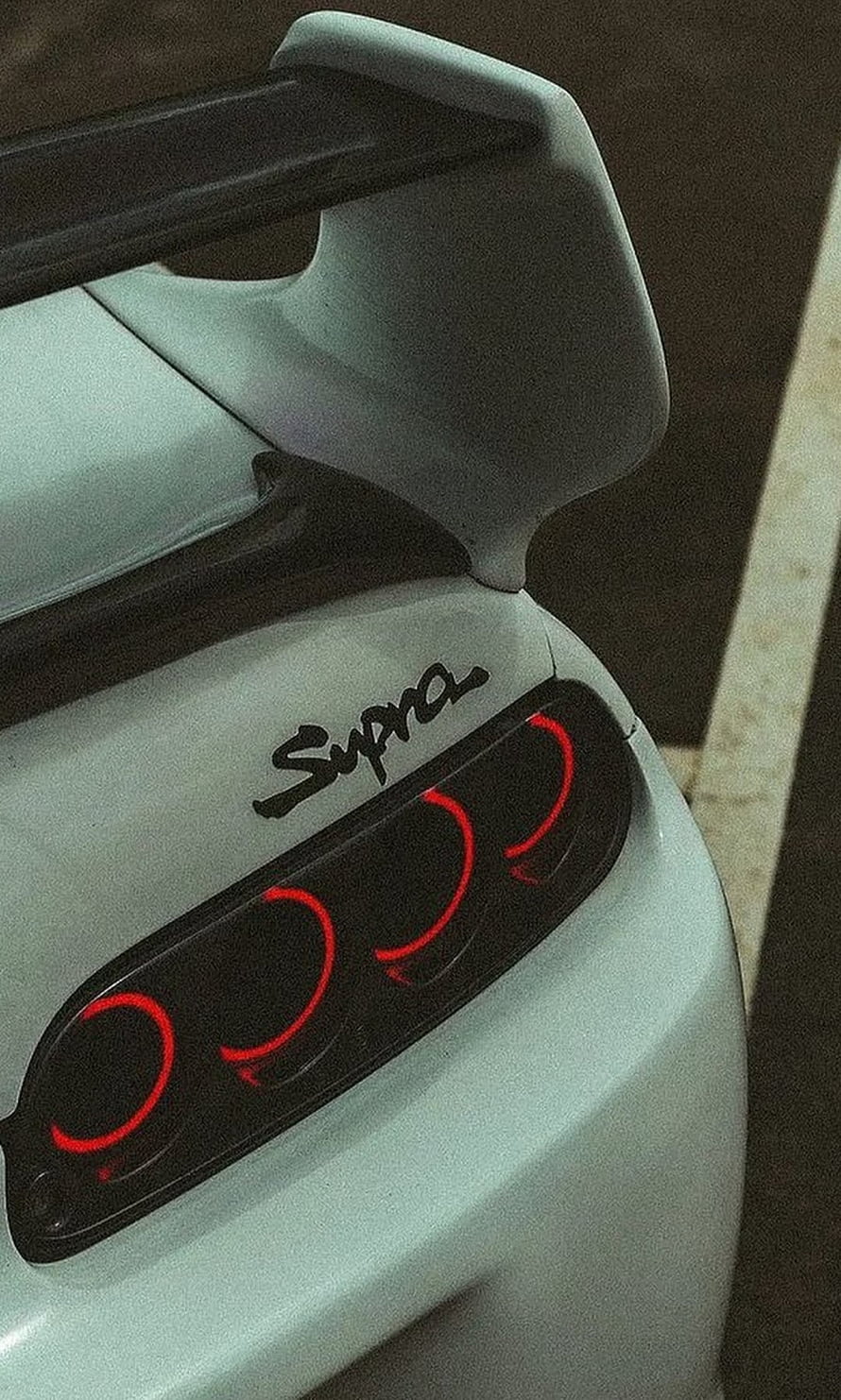 Close-up of a white Toyota Supra Mk4 rear quarter panel featuring the iconic triple taillight design and rear spoiler HD phone wallpaper