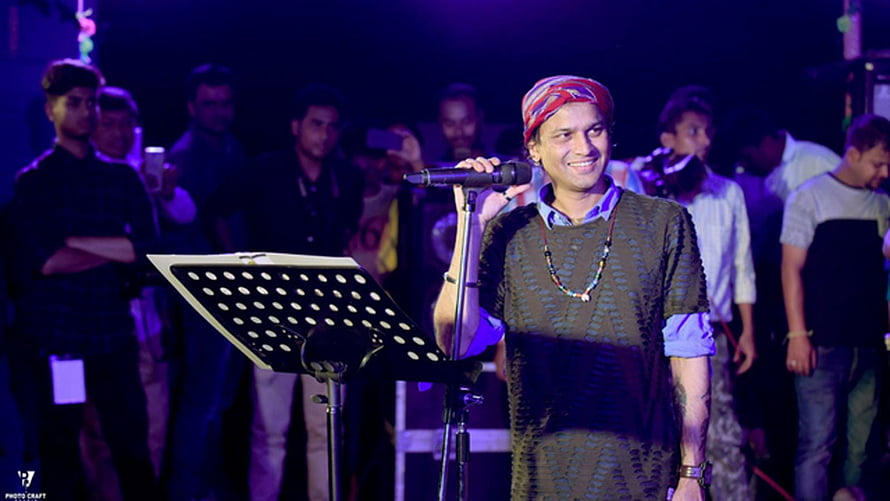 Zubeen Garg performing live on stage with microphone and music stand HD wallpaper