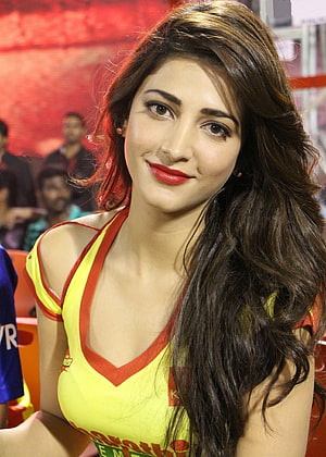 Shruti Hassan in a vibrant yellow and red top with long wavy hair and bold red lipstick HD phone wallpaper
