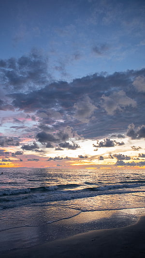 Serene Ocean Sunset with Dramatic Clouds and Gentle Waves on a Sandy Shore HD phone wallpaper
