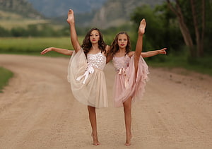 Two young ballerinas performing a graceful pose on a scenic country road HD wallpaper