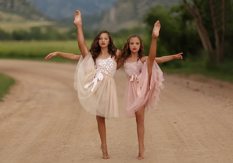 Two young ballerinas performing a graceful pose on a scenic country road HD wallpaper