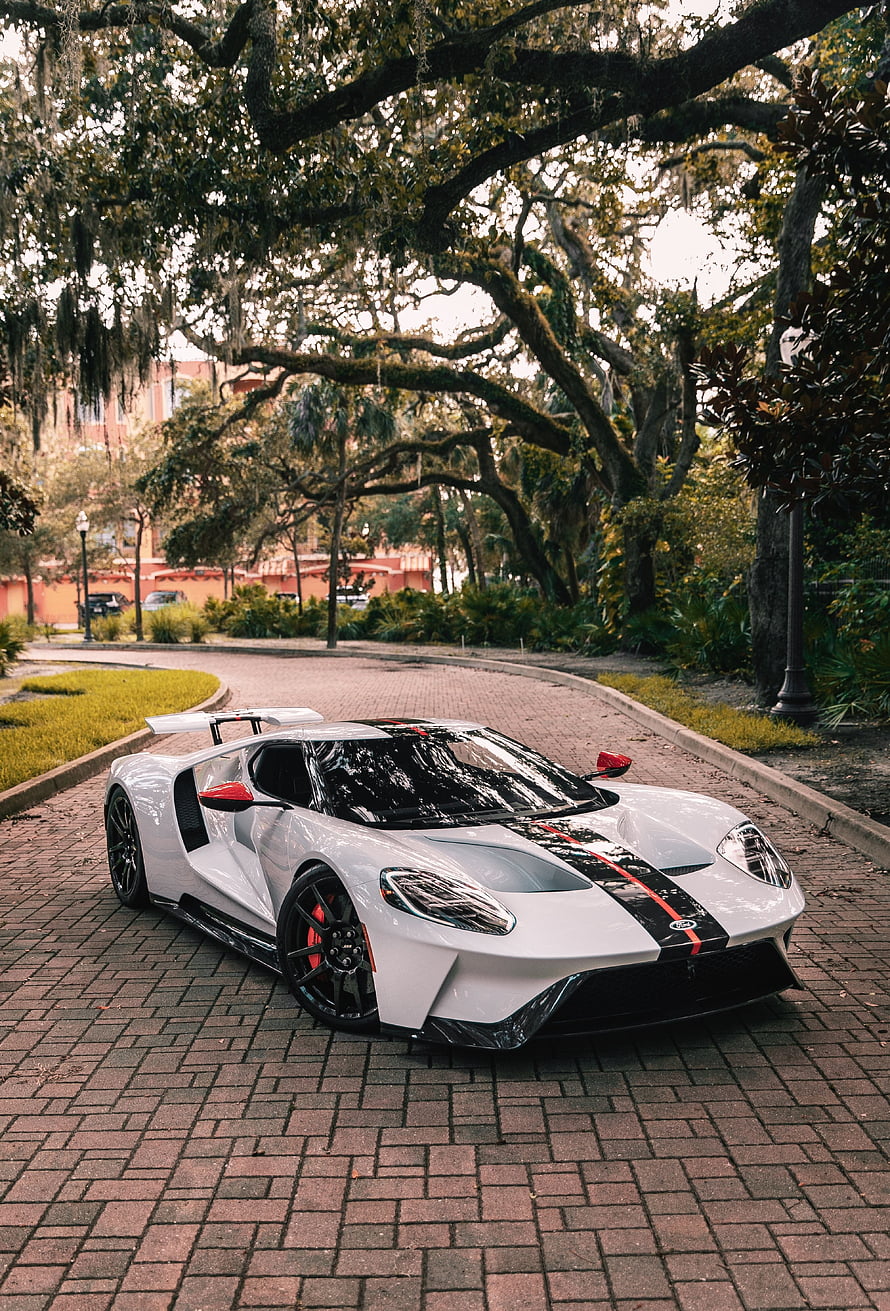 White Ford GT Super Car with Black Racing Stripes Parked on Brick Road Under Oak Trees HD phone wallpaper