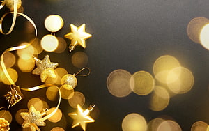 Elegant Gold Star Ornaments and Ribbons on Dark Background with Warm Bokeh Lights HD wallpaper