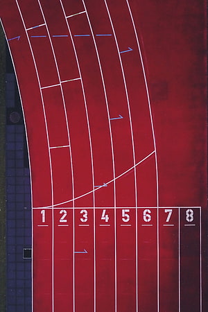 Aerial View of Red Athletics Track with Numbered Lanes and Start Line HD phone wallpaper