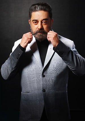 Kamal Haasan in a grey suit with a confident boxing stance against a dark studio background HD phone wallpaper