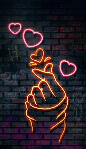 Neon Orange Hand Making Heart Gesture Against Dark Brick Wall With Pink Hearts HD phone wallpaper