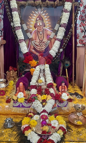 Swami Samarth Hindu Deity Idol Adorned With Flower Garlands And Peacock Feathers HD phone wallpaper