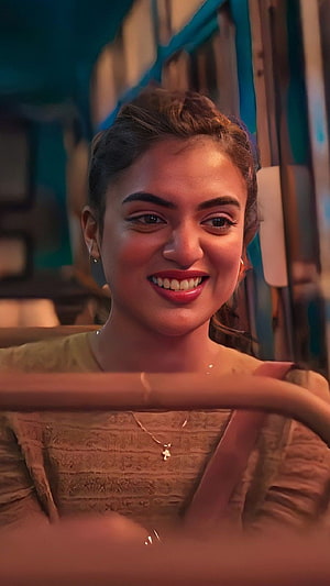 Nazriya Nizam smiling warmly in a vintage car with warm cinematic lighting HD phone wallpaper
