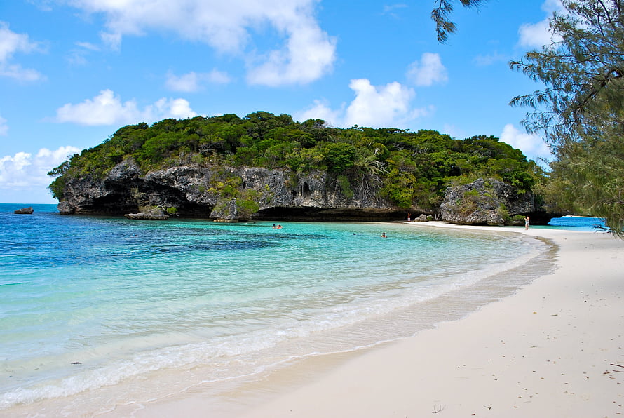 Tropical Island Beach With Turquoise Water, White Sand, and Lush Rocky Headland HD wallpaper