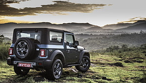 Mahindra Thar SUV parked on a grassy hillside with a misty mountain range at sunset HD wallpaper