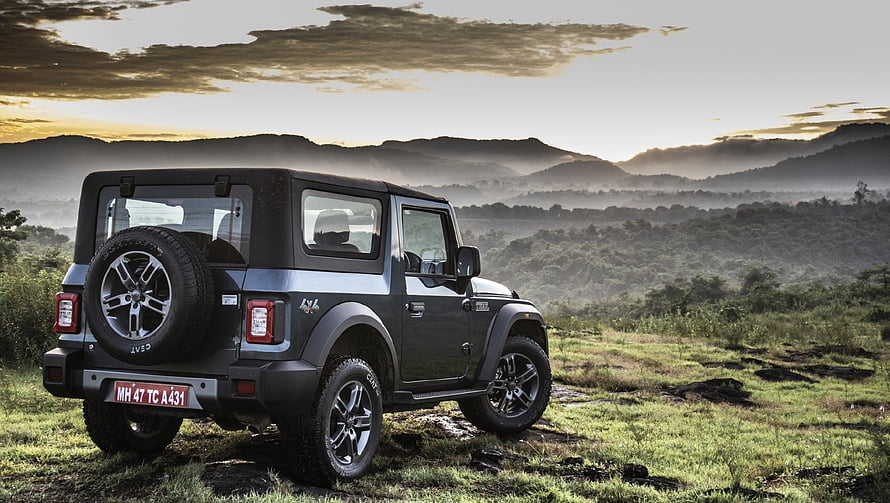 Mahindra Thar SUV parked on a grassy hillside with a misty mountain range at sunset HD wallpaper