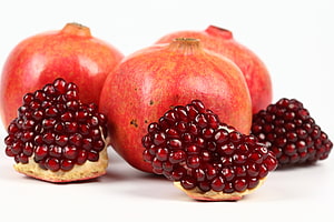 Fresh Pomegranates with Exposed Ruby Arils on a Clean White Background HD wallpaper