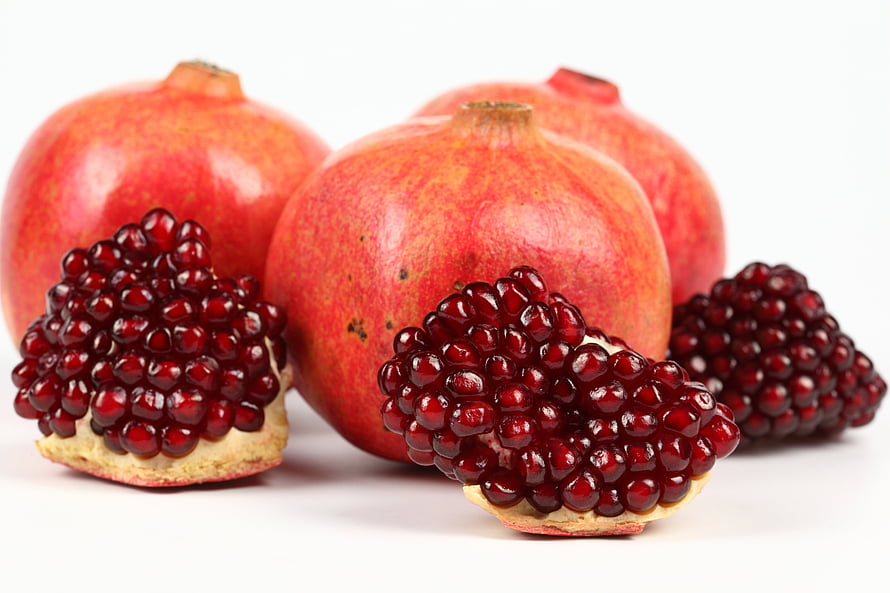 Fresh Pomegranates with Exposed Ruby Arils on a Clean White Background HD wallpaper