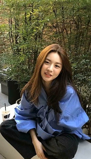 Go Yoon Jung in a blue shirt sitting outdoors with greenery HD phone wallpaper