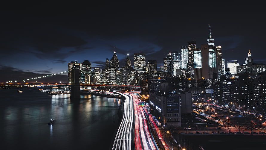 New York City Skyline at Night with Brooklyn Bridge and Long Exposure Traffic Trails HD wallpaper