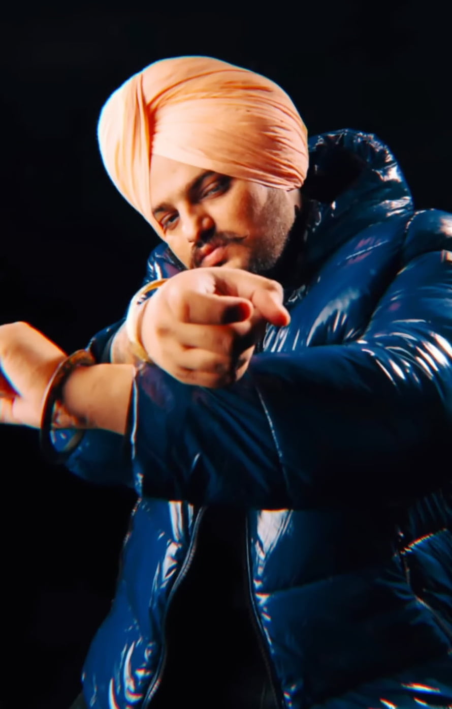 Sidhu Moosewala in a blue puffer jacket and peach turban pointing forward HD phone wallpaper