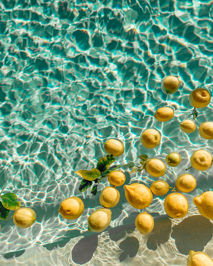 Fresh Lemons Floating in Turquoise Pool Water with Sunlight Caustics HD phone wallpaper