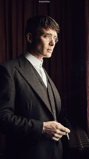 Tommy Shelby in a dark three-piece suit holding a cigarette with a somber expression HD phone wallpaper
