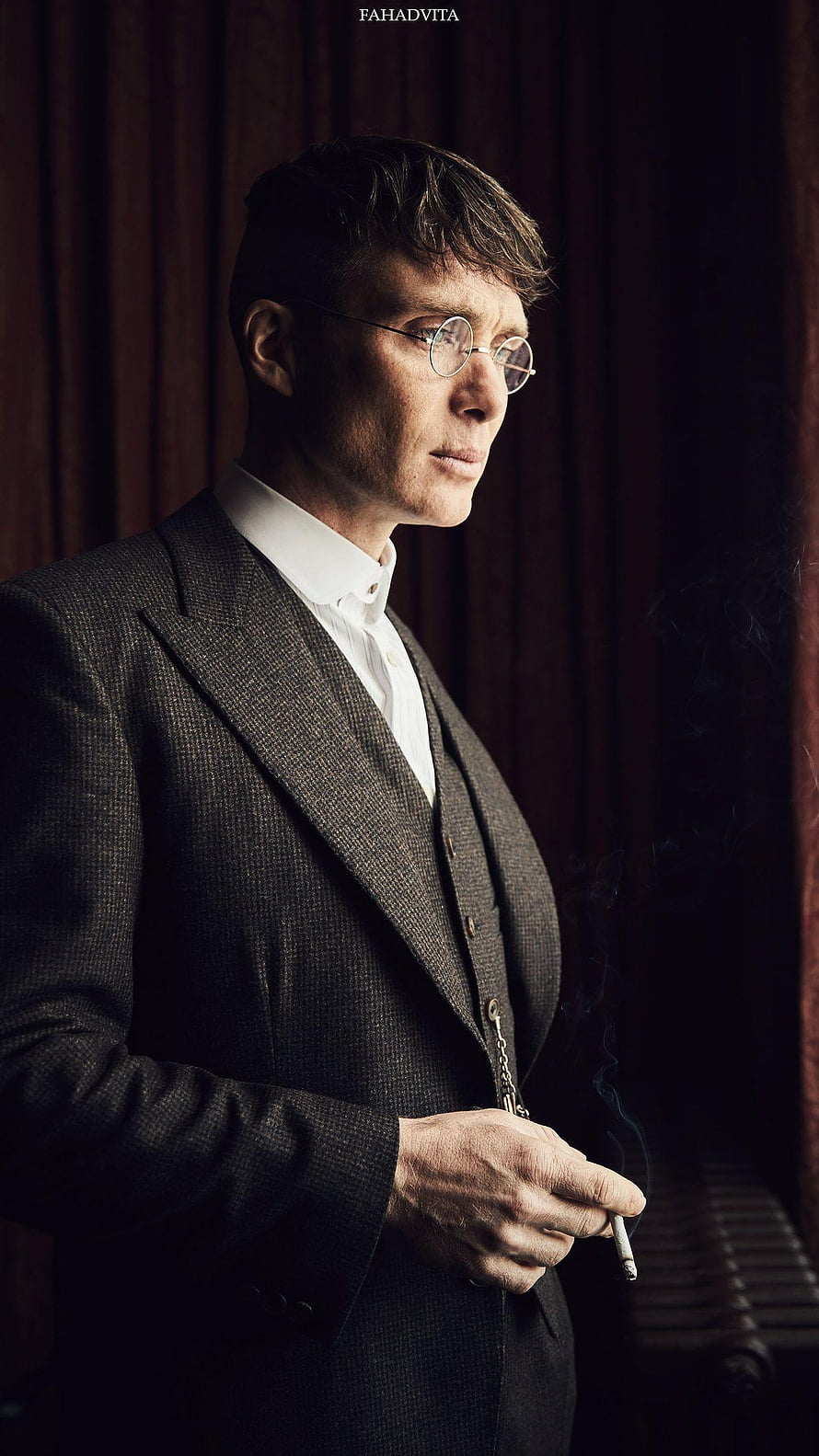 Tommy Shelby in a dark three-piece suit holding a cigarette with a somber expression HD phone wallpaper