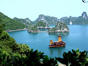 Traditional Junk Boat Sailing Through Limestone Karst Islands in Ha Long Bay HD wallpaper