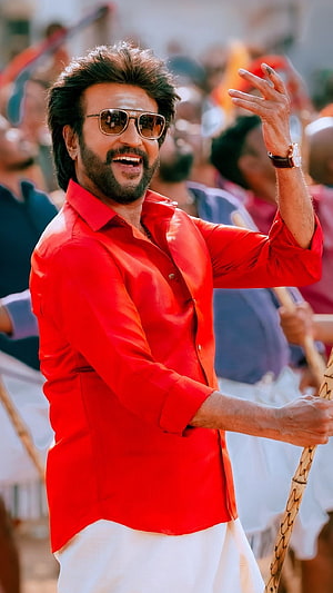 Rajinikanth in a vibrant red shirt and sunglasses during a lively outdoor scene HD phone wallpaper