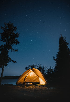 Glowing Camping Tent Under a Starry Night Sky by a Quiet Lake HD phone wallpaper