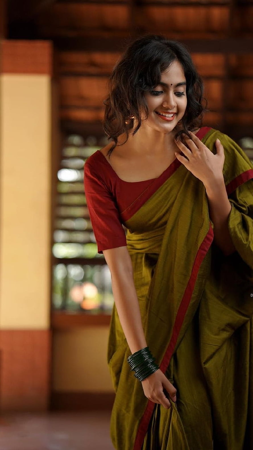 Indian woman smiling in an olive green saree with a deep red blouse and traditional bangles HD phone wallpaper
