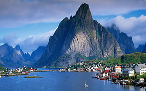 Dramatic fjord landscape with steep rocky peaks and a coastal village HD wallpaper