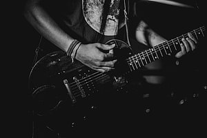 Black and white close-up of a musician playing an electric guitar on stage HD wallpaper