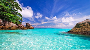 Tropical Turquoise Lagoon With Granite Boulders And Lush Green Foliage Under A Bright Blue Sky HD wallpaper