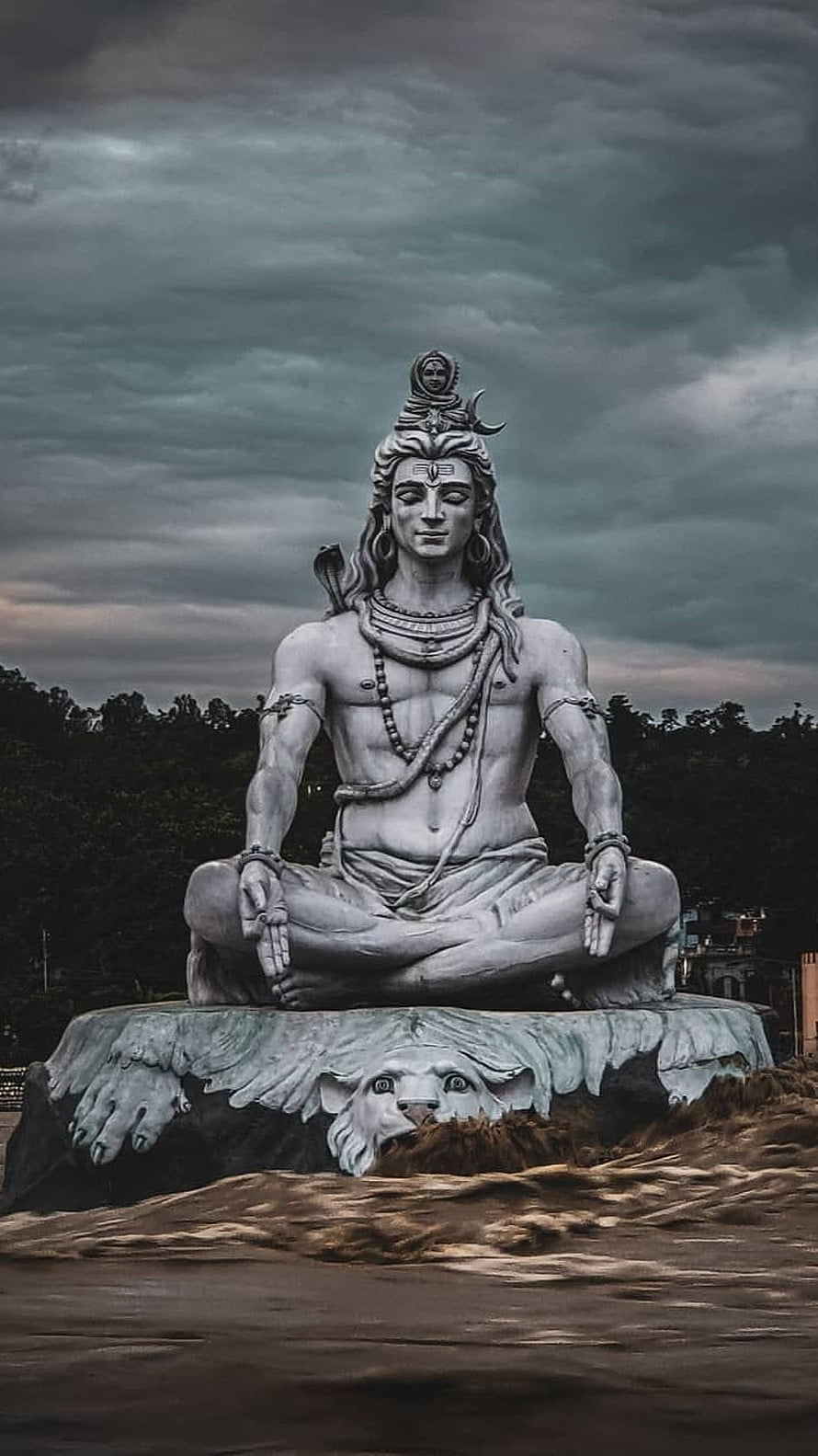Meditating Shiva Statue Seated on Eagle Pedestal Under Dramatic Stormy Sky HD phone wallpaper