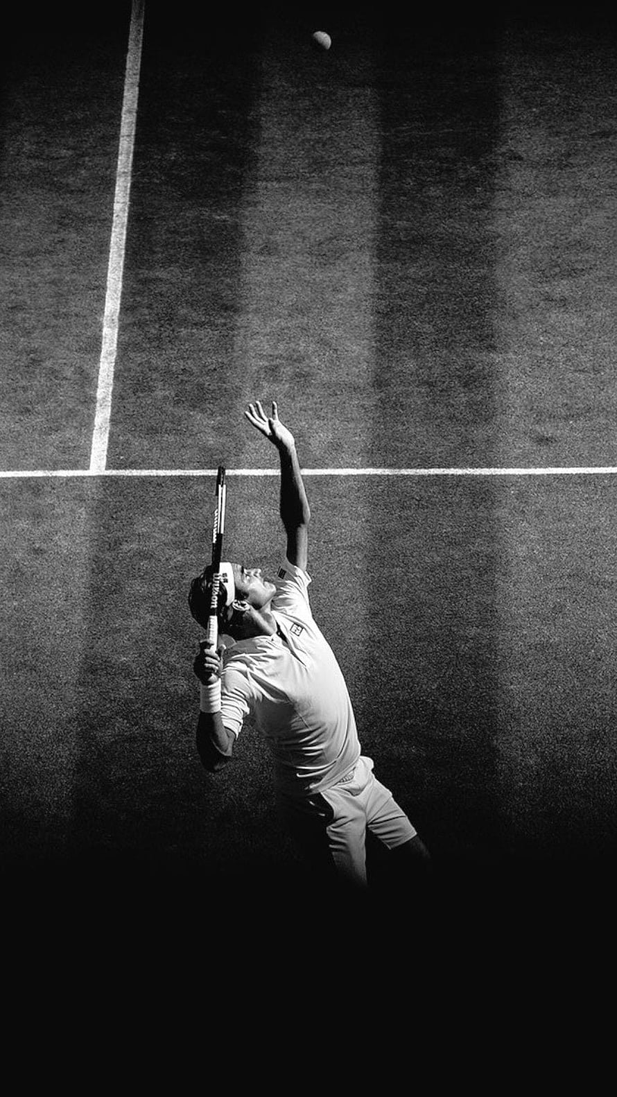 Roger Federer Serving on a Grass Court in Black and White HD phone wallpaper