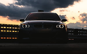 Black BMW M5 E60 Front View at Sunset with Dramatic Clouds and Angel Eyes HD wallpaper