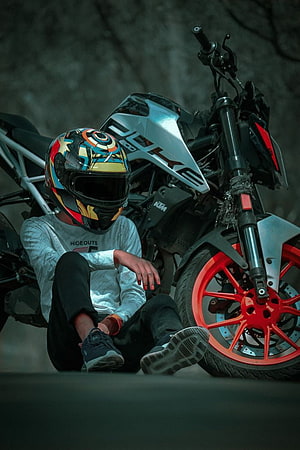 Motorcyclist in colorful helmet sitting beside a KTM Duke motorcycle with red wheels HD phone wallpaper