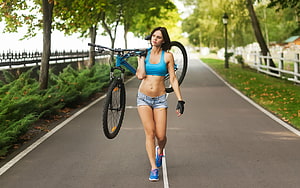 Athletic Woman Walking With Mountain Bike On Tree-Lined Park Path HD wallpaper