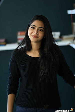 Aishwarya Lekshmi in a black knit sweater with long dark hair and a soft smile HD phone wallpaper