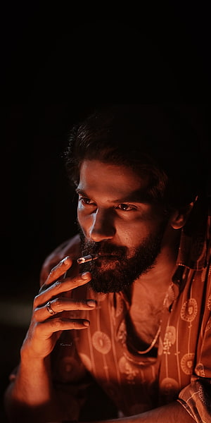 Dulquer Salmaan in moody low-light portrait smoking a cigarette HD phone wallpaper
