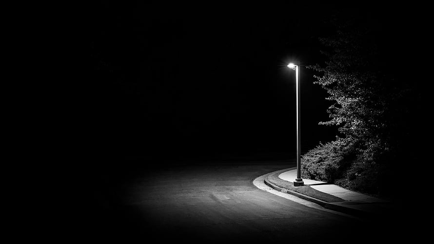 Solitary Street Lamp Illuminating a Curved Road at Night in Black and White HD wallpaper